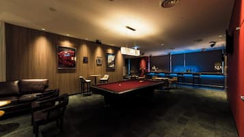 A pool table in a dimly lit room with a bar area and seating.