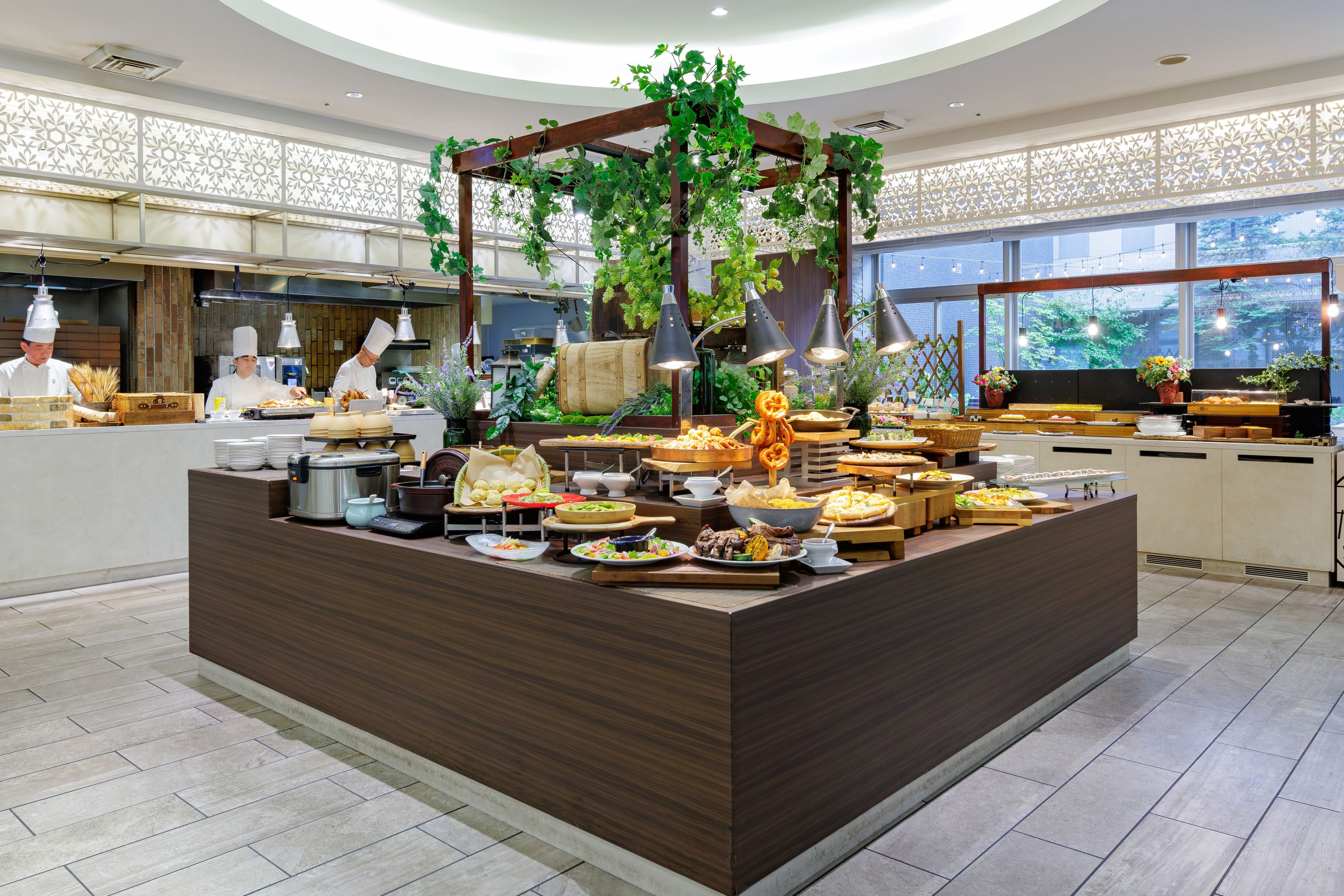 Un buffet proposant divers plats, un chef en uniforme et, au fond, un espace cuisine.