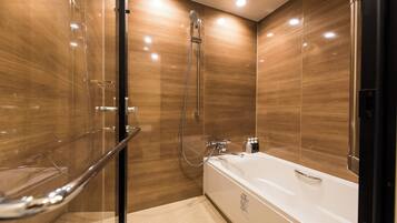 A modern bathroom with a glass shower enclosure, a white bathtub, and wooden paneling.