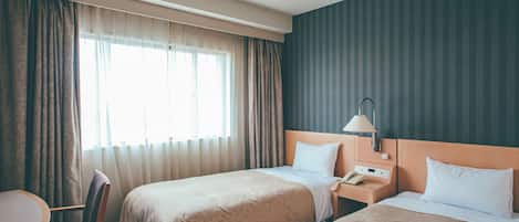 A hotel room with two beds, a desk, and a chair.
