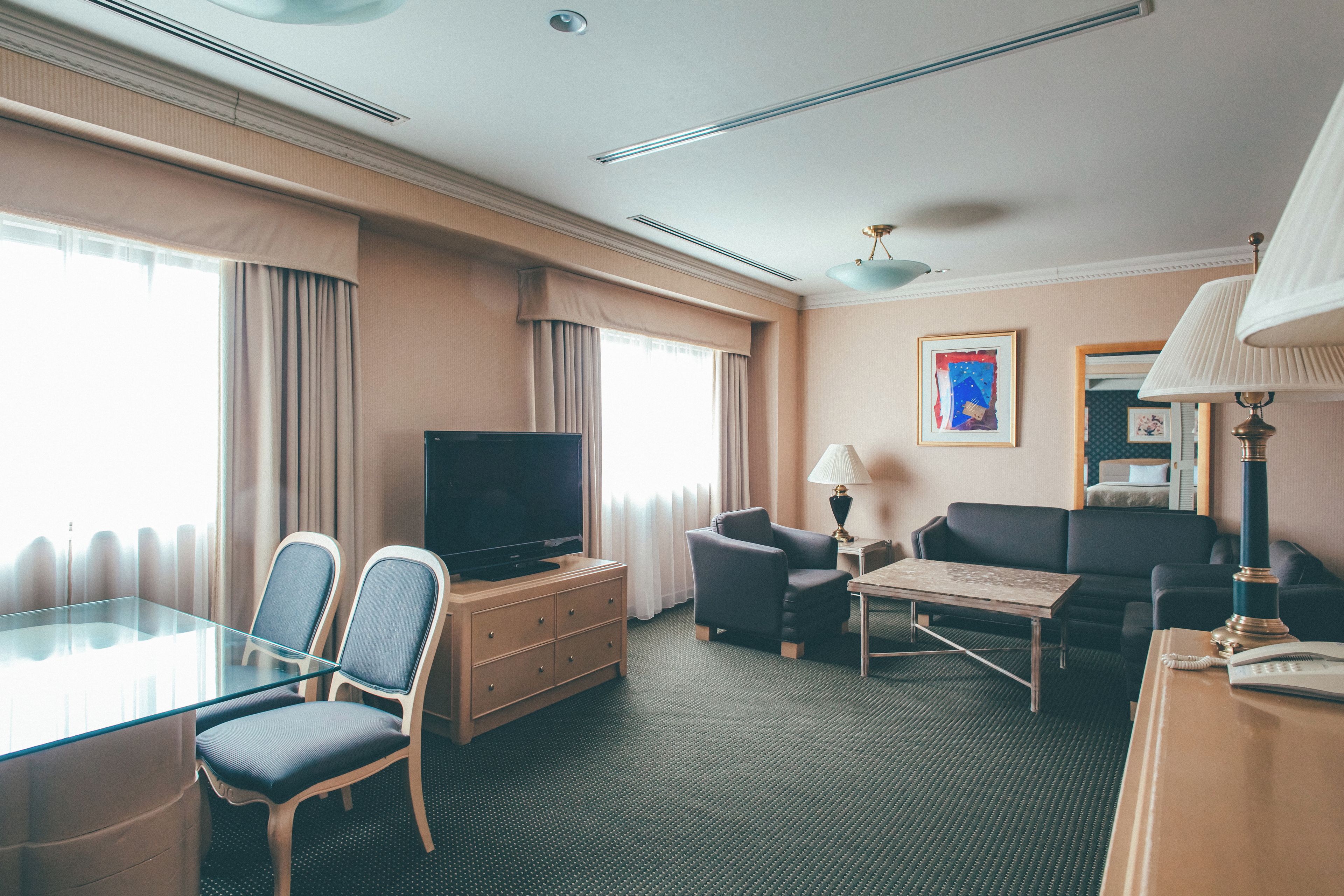 A hotel room with a television, two armchairs, a sofa, a small table, and a lamp.