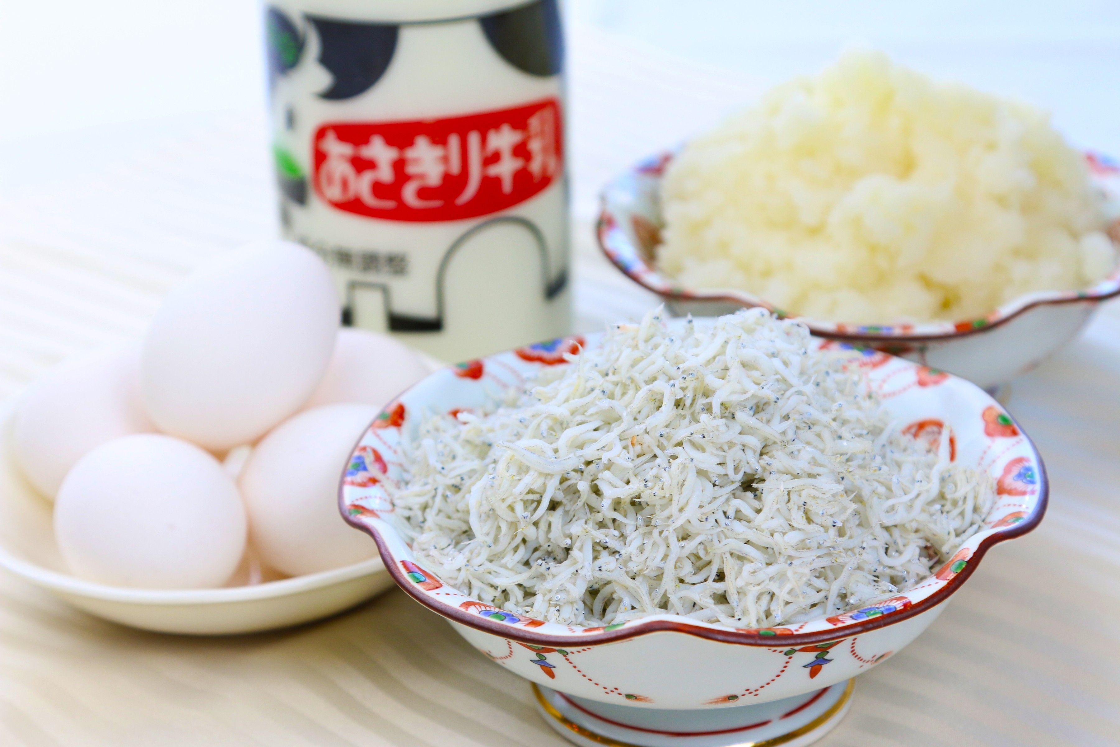 A table with bowls containing eggs, shredded cabbage, and a canister with a label.