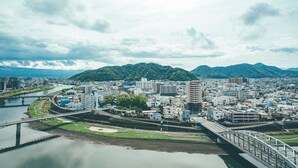 A cityscape with a river, a bridge, and mountains in the background. - Numazu Riverside Hotel (Numazu)