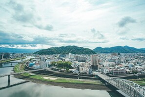 Paisagem urbana com rio, ponte e montanhas ao fundo.