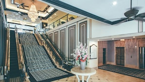 A hotel lobby with a grand staircase, a reception desk, and a decorative vase. - Numazu Riverside Hotel (Numazu)