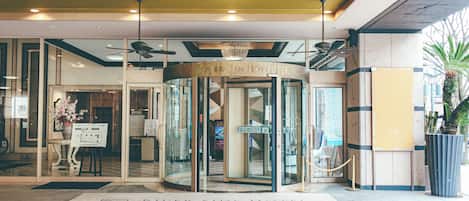 A hotel entrance with a revolving door, glass doors, and a sign above the door.