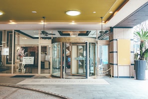 A hotel entrance with a revolving door, glass doors, and a sign above the door.