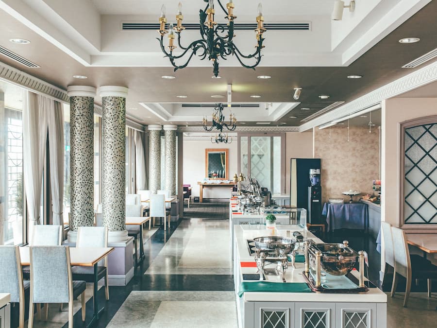Un comedor de hotel con una barra larga, varias mesas y un candelabro.