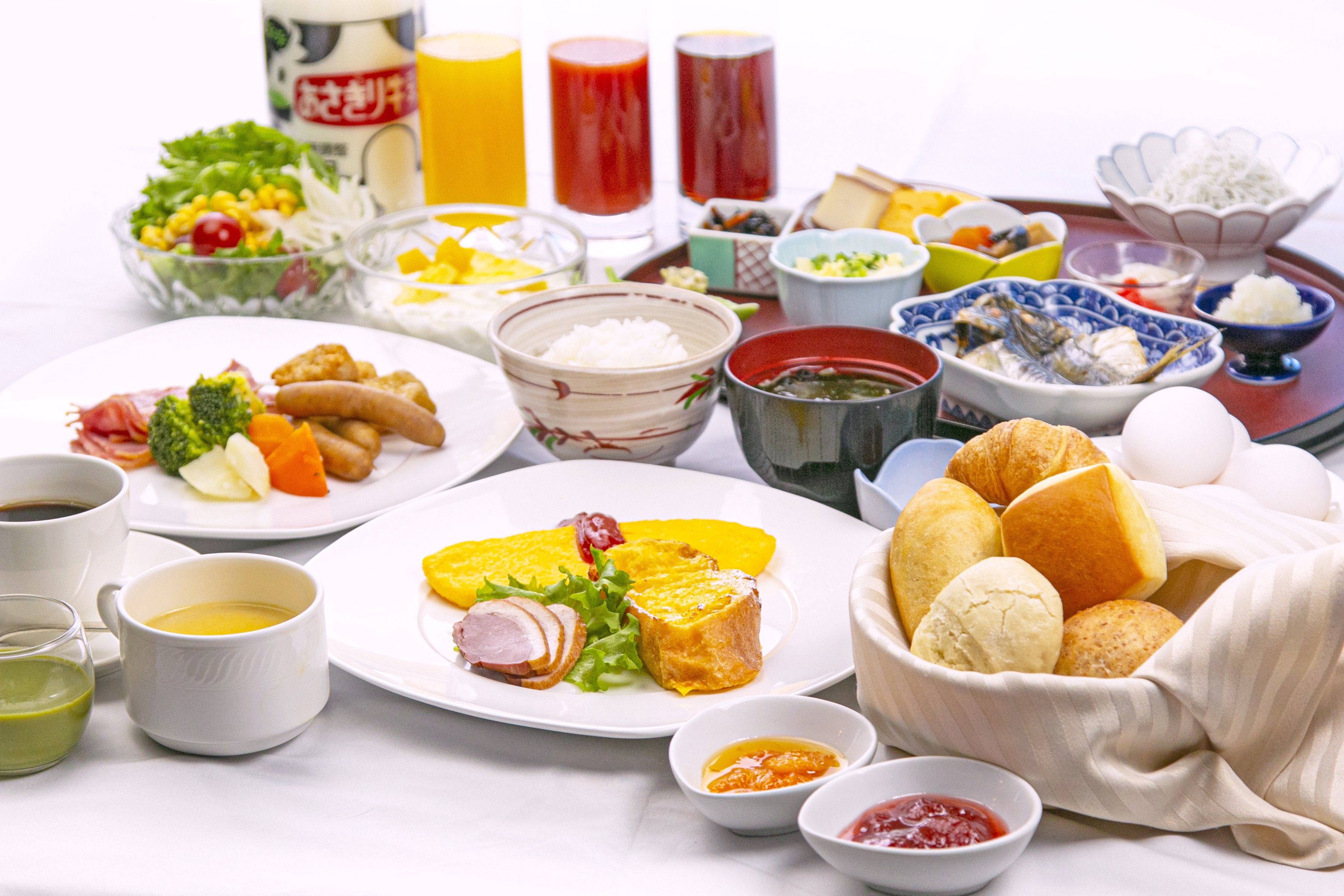 A variety of dishes and beverages on a table, including plates of food, bowls, and cups.
