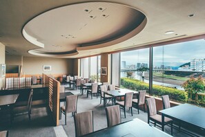 A modern restaurant with high ceilings, large windows, and a view of a cityscape.