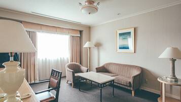 A hotel room with a bed, a desk, a chair, a sofa, a lamp, and a painting on the wall.