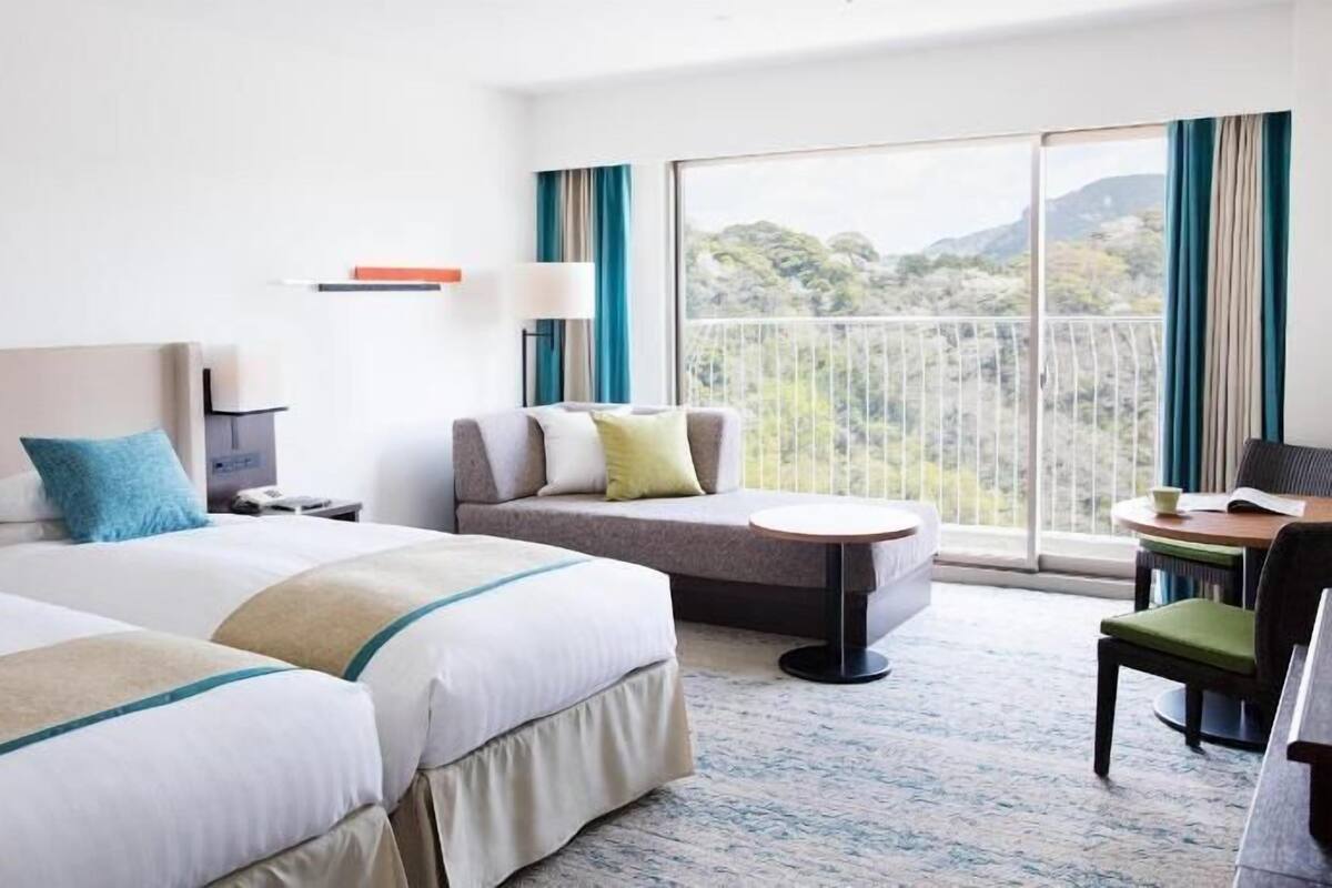 A hotel room with two beds, a sofa, a small table, and a chair.