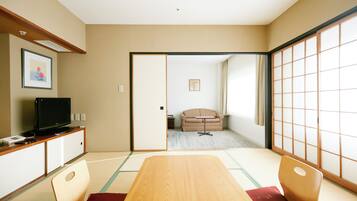 Una habitación japonesa tradicional con suelo de tatami, una mesa baja y un televisor sobre un mueble.