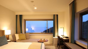 Habitación de hotel con una cama grande, un escritorio, una silla y vistas al mar.