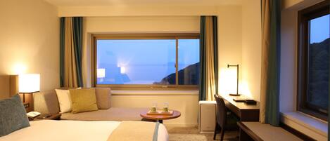 Habitación de hotel con una cama grande, un escritorio, una silla y vistas al mar.