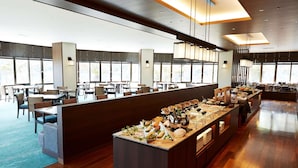 Un amplio comedor de hotel con varias mesas y una barra de buffet.