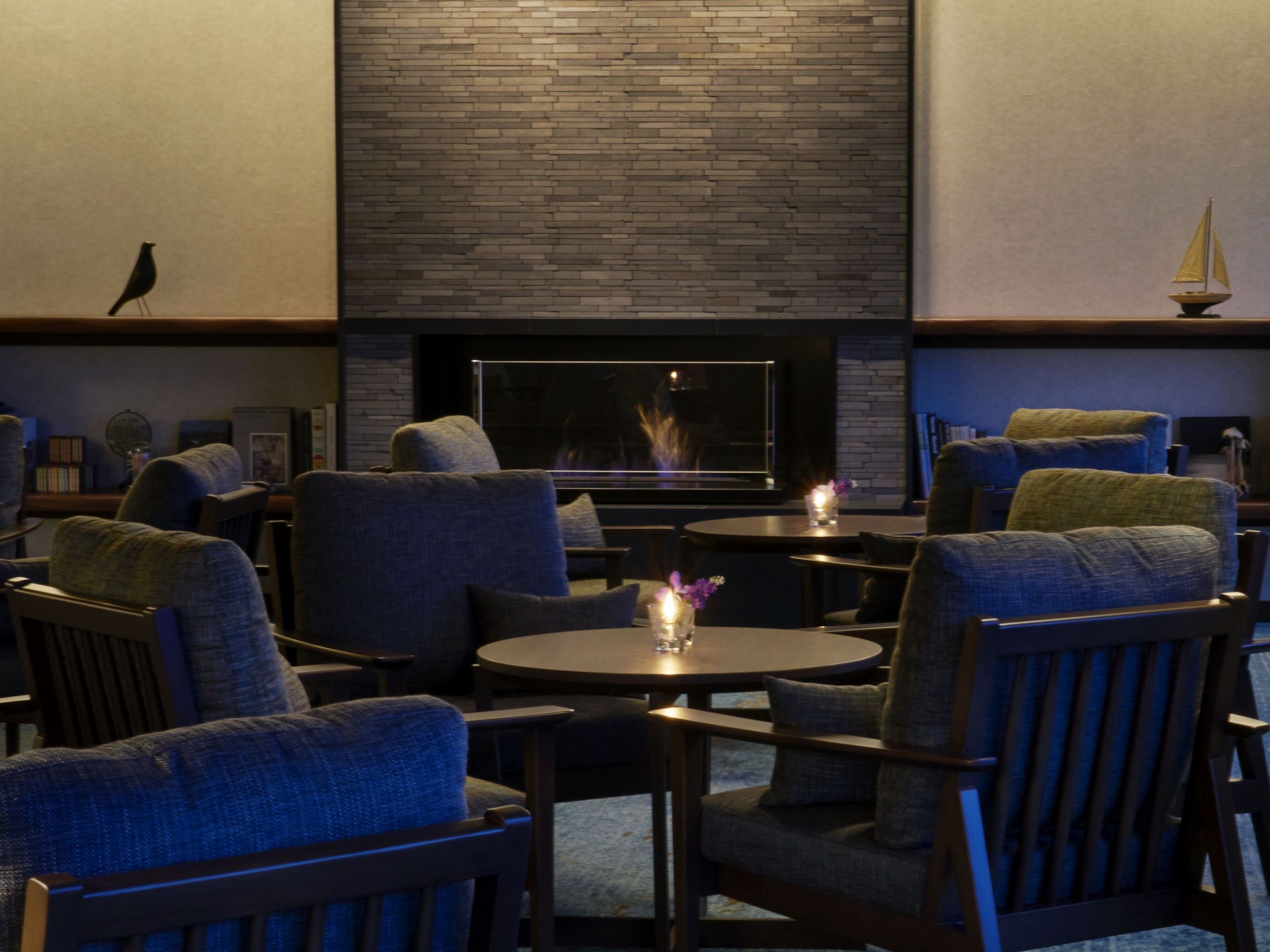 A cozy lounge area with modern furniture, a fireplace, and a small sailboat decoration.