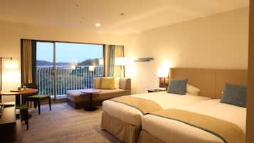 Habitación de hotel con dos camas, un sofá, una mesita y un balcón con vistas.