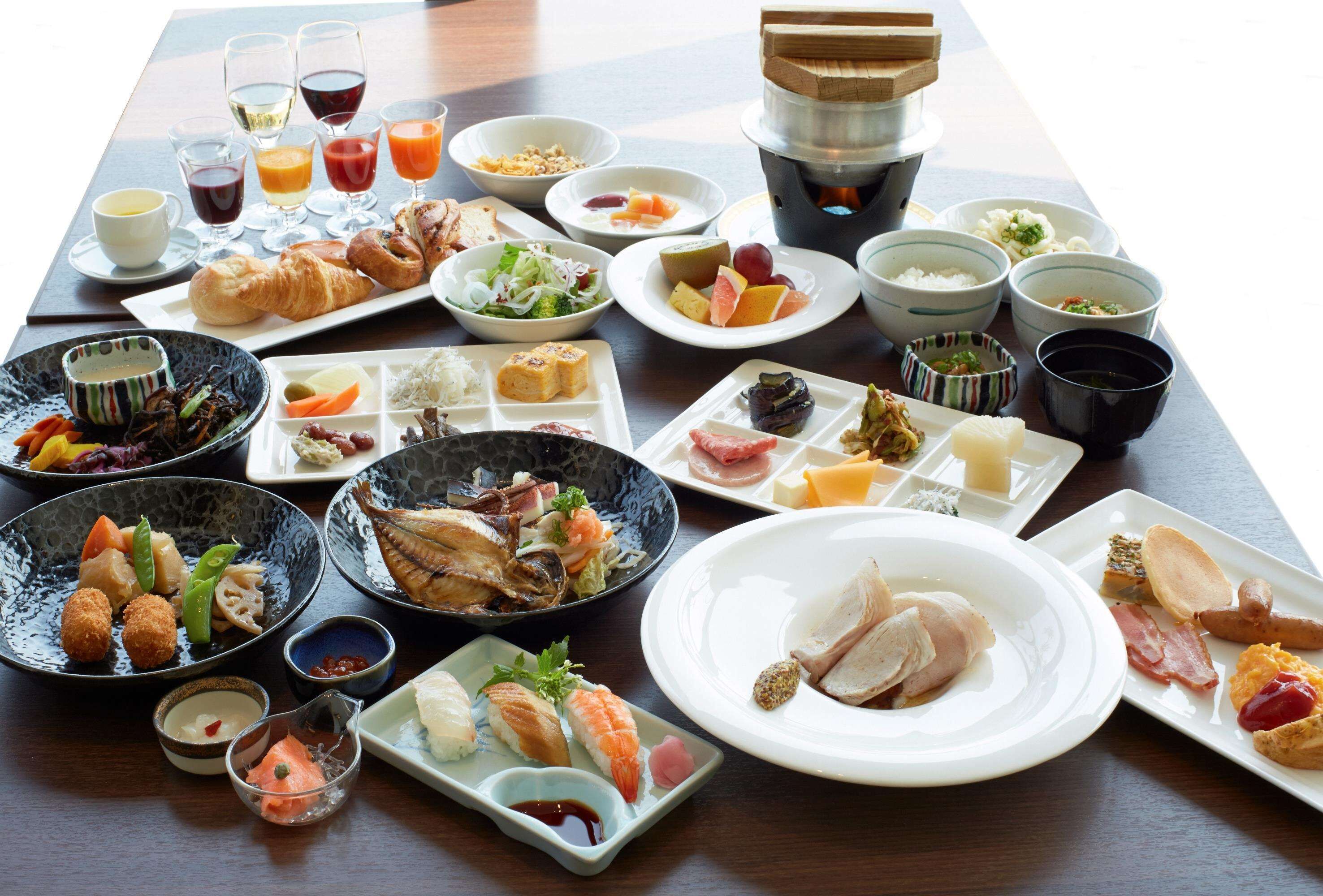 A variety of dishes and drinks on a table, including sushi, sashimi, and a teapot.