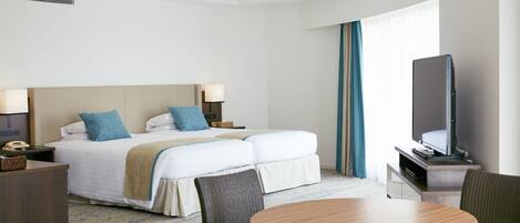 A hotel room with a bed, a TV, a desk, and a dining table.