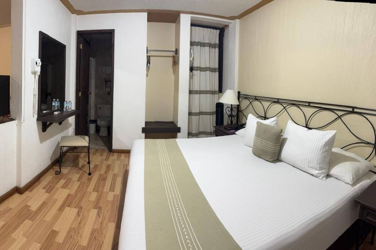 A hotel room with a bed, a desk, a television, and a bathroom.