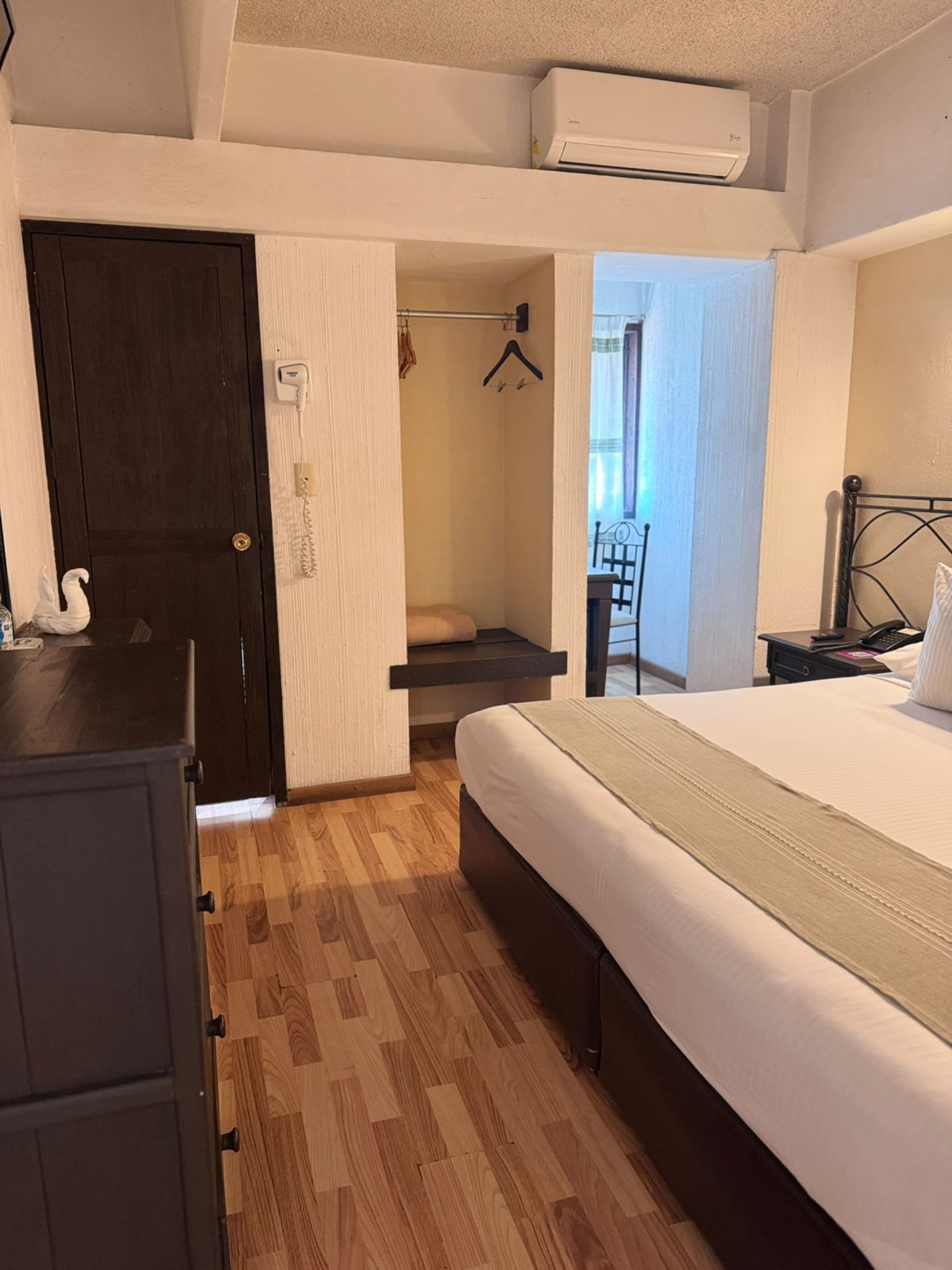 Un dormitorio con cama, armario, perchero y equipo de aire acondicionado.