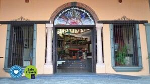 A hotel entrance with a decorative archway, a staircase leading inside, and a sign indicating 'Safe travels'.