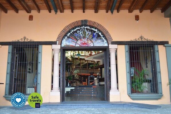 A hotel entrance with a decorative archway, a staircase leading inside, and a sign indicating 'Safe travels'. - Hotel Misión Xalapa (Xalapa)