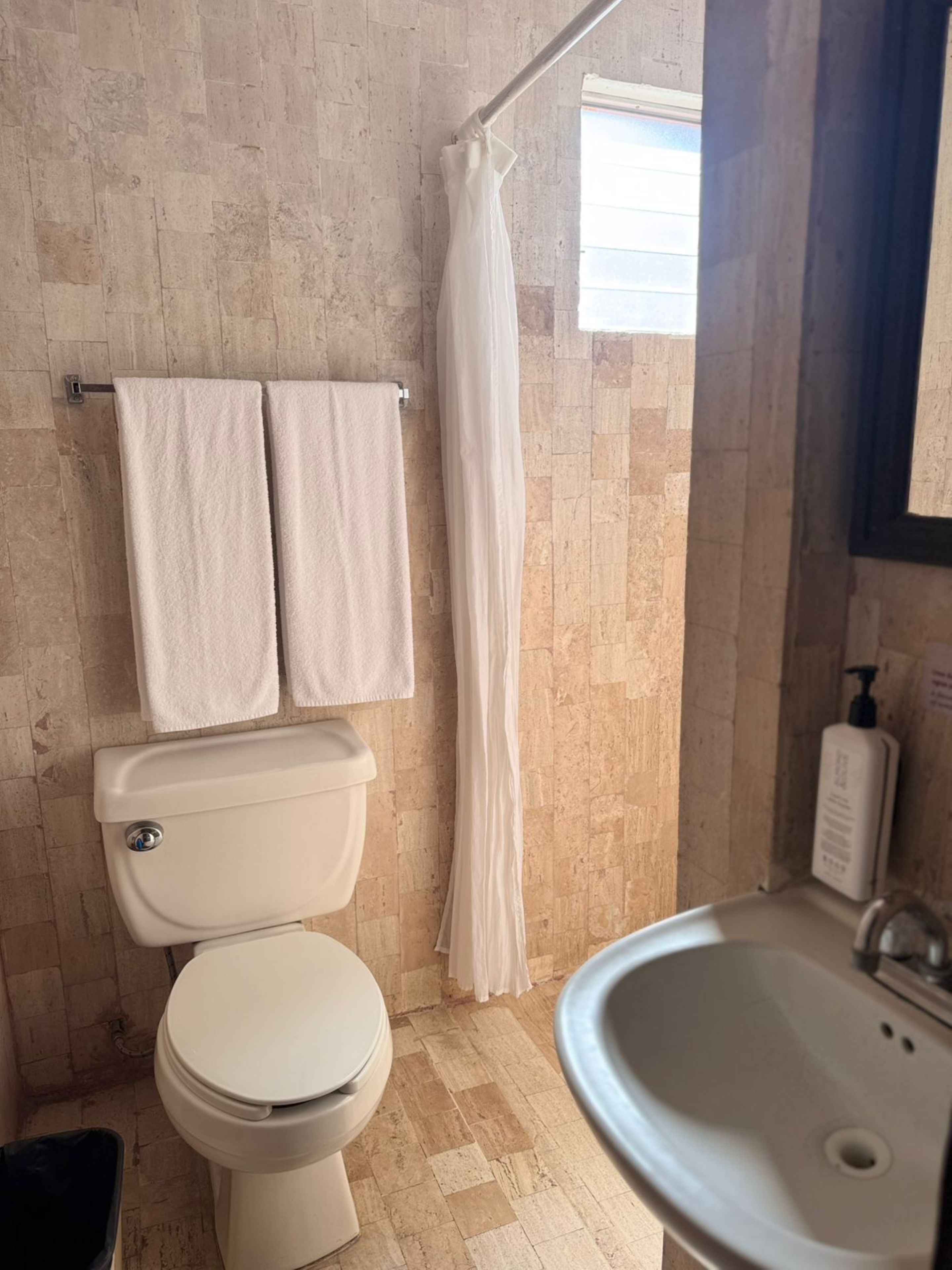 Baño con inodoro, lavabo y cortina de ducha.