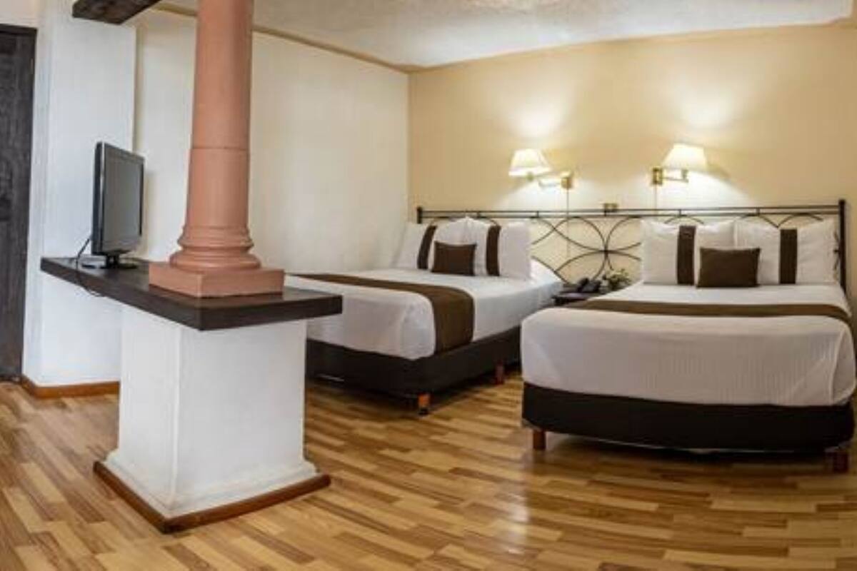 A hotel room with two beds, a TV, and a lamp.