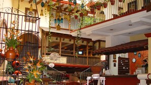 A spacious lobby with a staircase, multiple potted plants, and a reception desk.