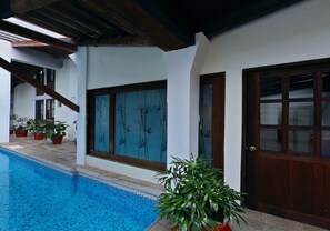 An indoor swimming pool with a wooden ceiling, white walls, and a large window with a view of trees. - Hotel Misión Xalapa (Xalapa)