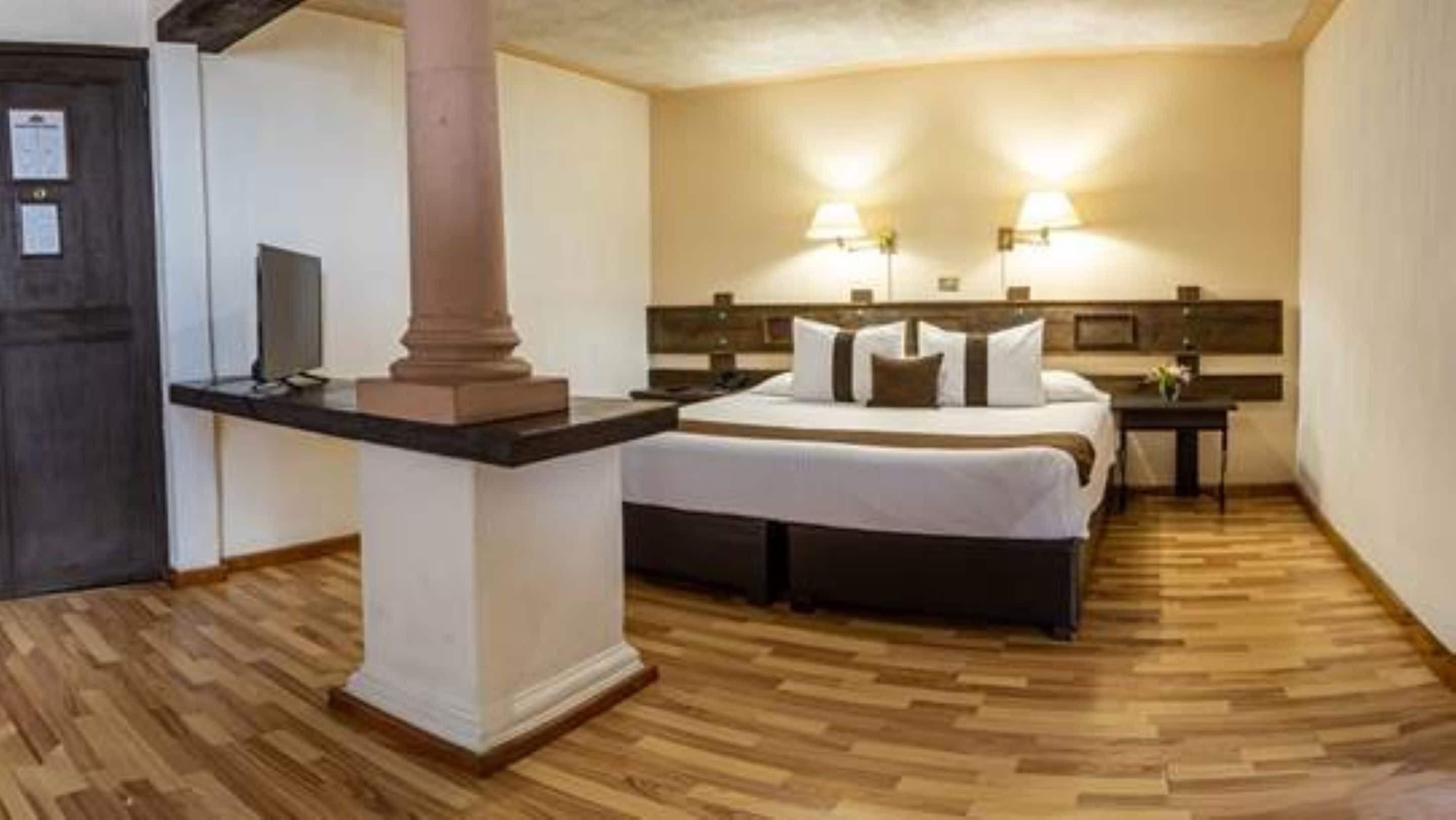Ein Hotelzimmer mit einem Bett, Nachttischen, einem Schreibtisch und einer Säule.