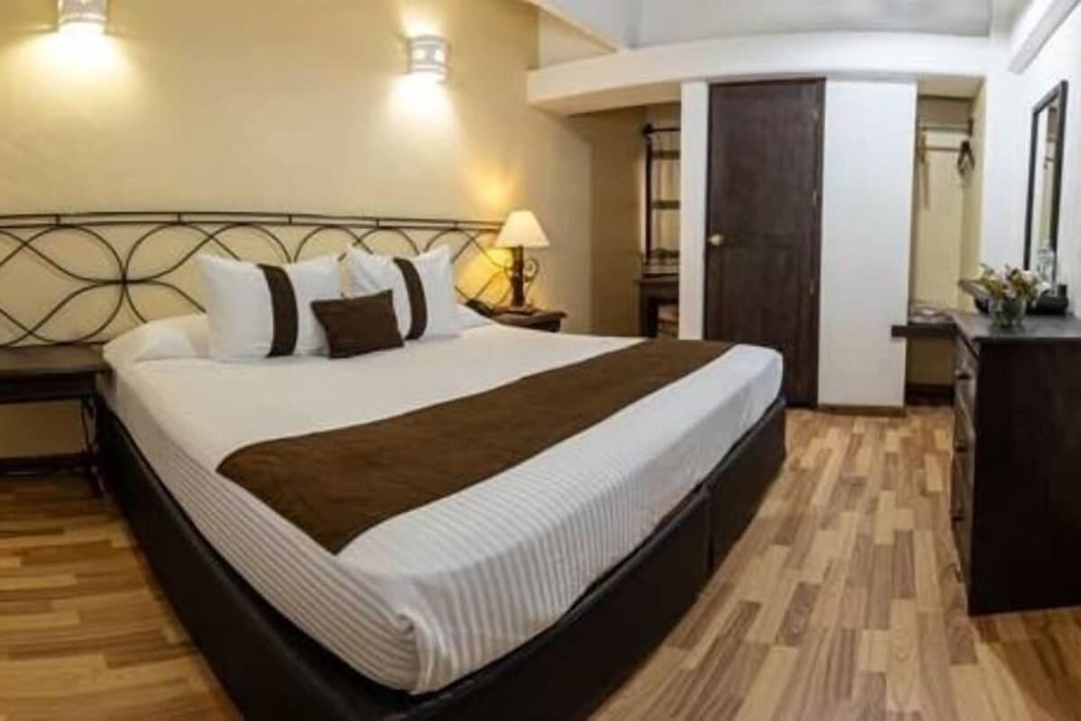 A bedroom with a bed, bedside tables, a lamp, and a wardrobe.