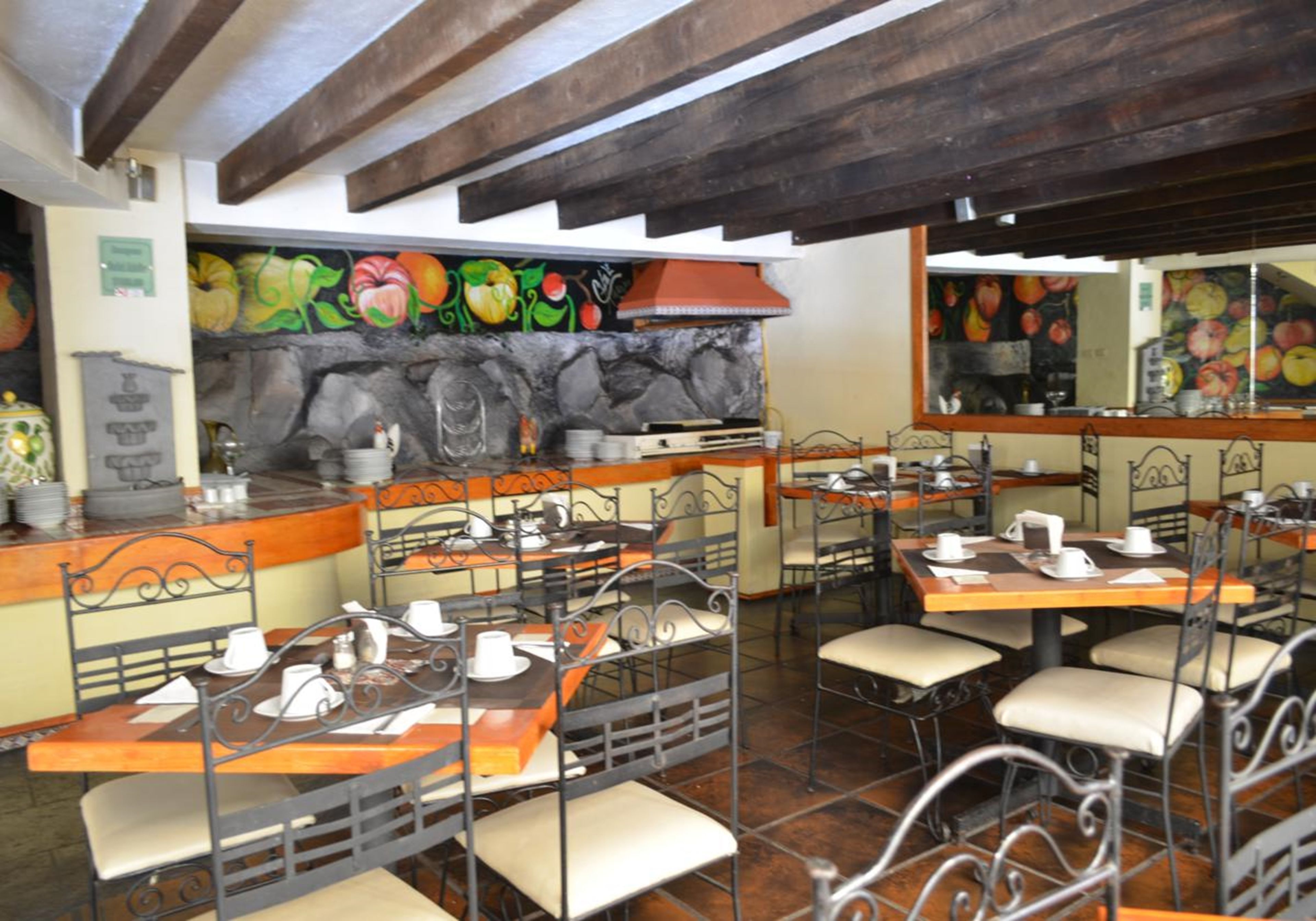 A restaurant with outdoor seating, stone walls, and fruit-themed murals.