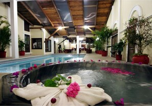 A spa area with a large hot tub surrounded by potted plants and flowers. - Hotel Misión Xalapa (Xalapa)