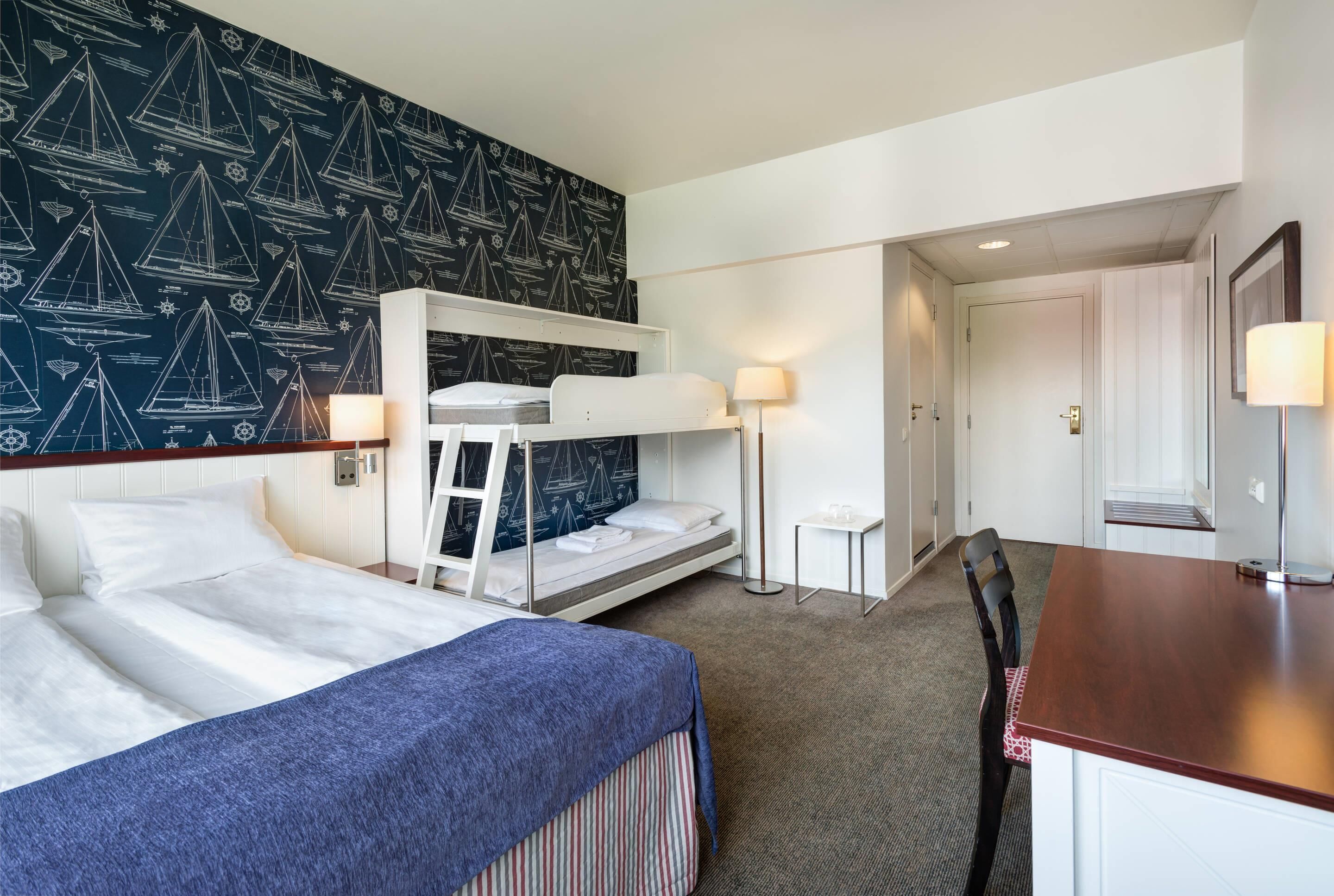 A hotel room with a bunk bed, a desk, and a small table.