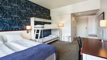 Una habitación de hotel con literas, un escritorio y una mesita.