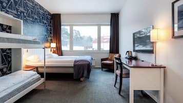 A hotel room with a bunk bed, a single bed, a desk with a chair, a TV, and a window with curtains.