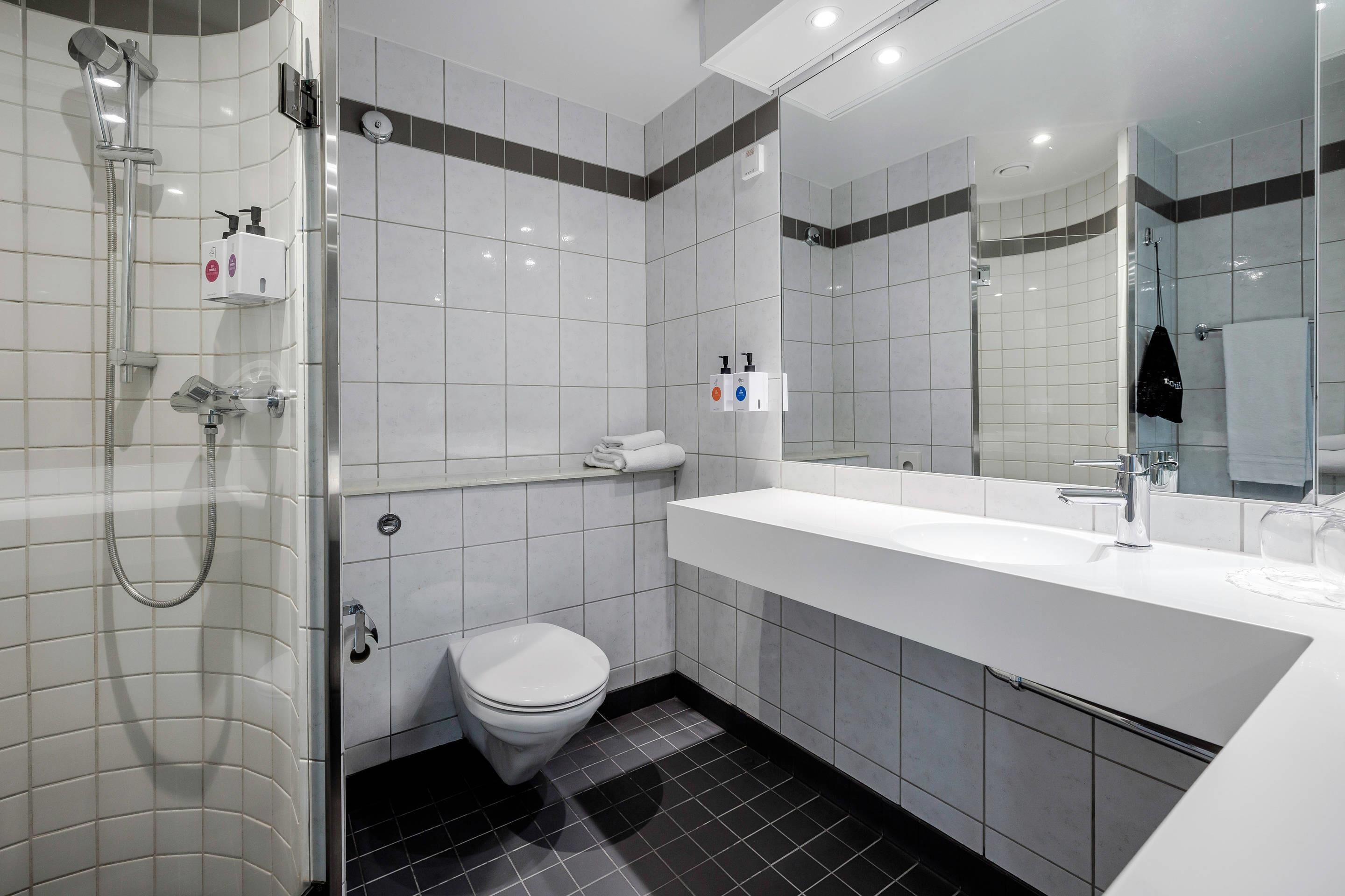 A modern bathroom with a shower, toilet, and sink.