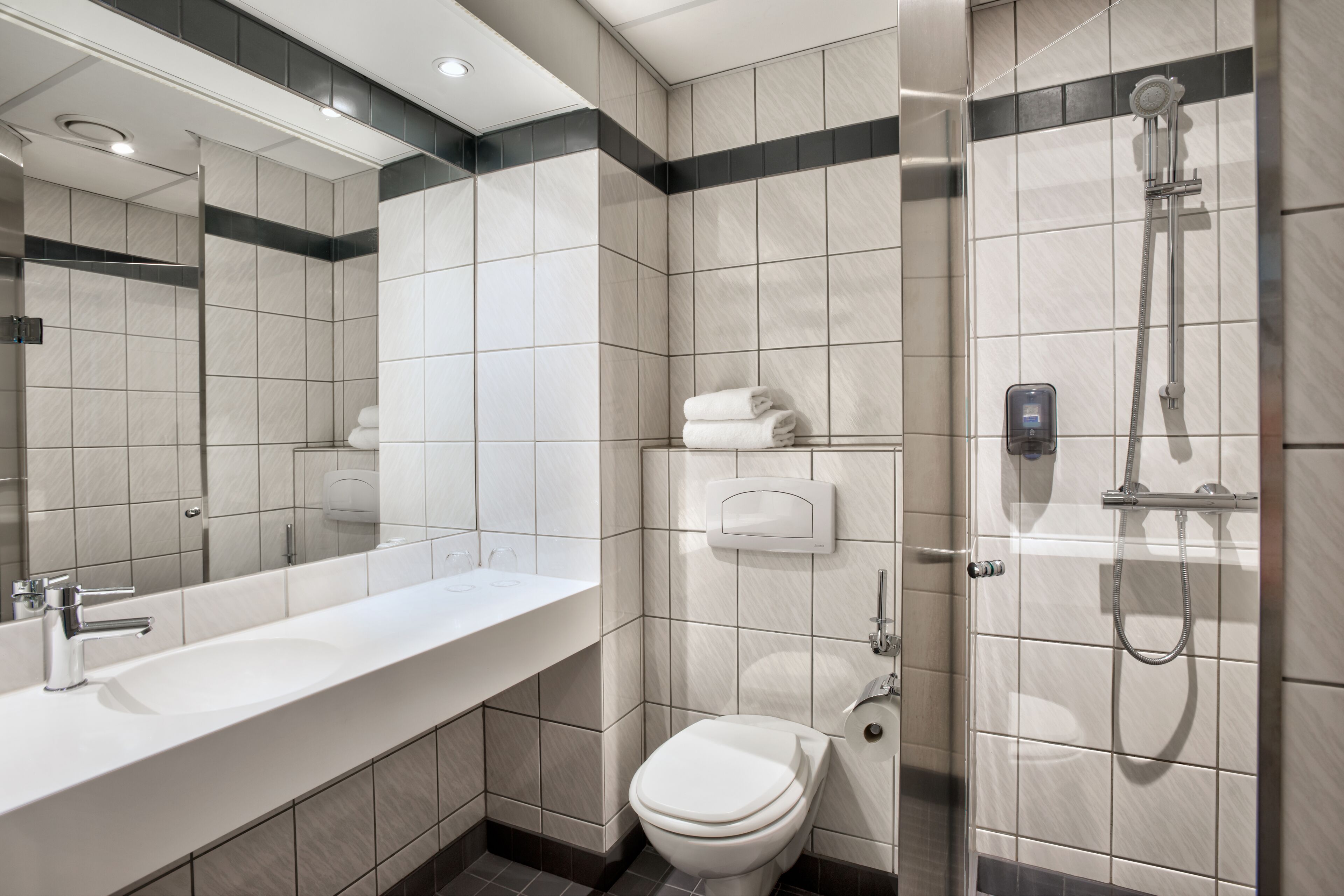 Un baño moderno con un lavabo blanco, inodoro y ducha.