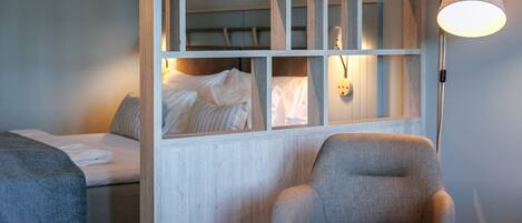 A hotel room with a bed, a chair, and a lamp.