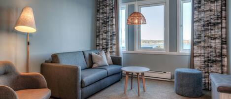 Una sala moderna con un sofá, un sillón, un reposapiés y una lámpara.