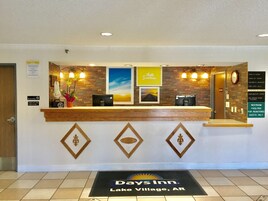 A reception desk at Days Inn in Lake Village, AR, with a check-in counter, a clock, and a sign listing amenities like continental breakfast and non-smoking rooms.
