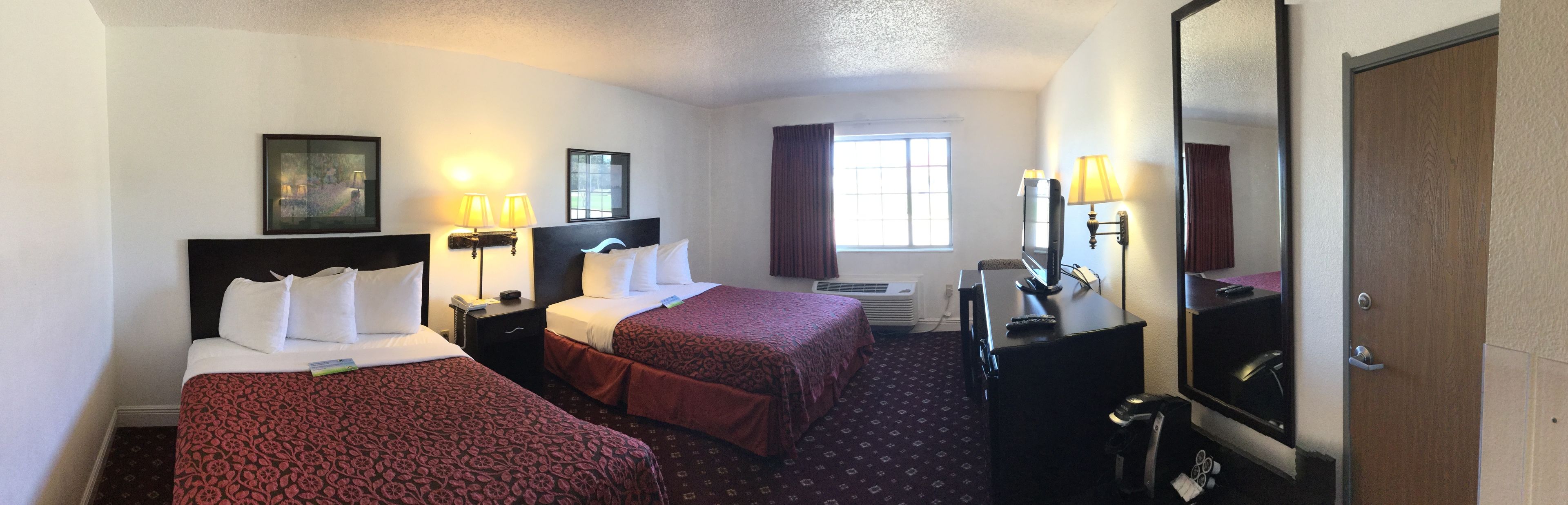 Une chambre d’hôtel avec deux lits, un bureau, une chaise, une télévision et un miroir.