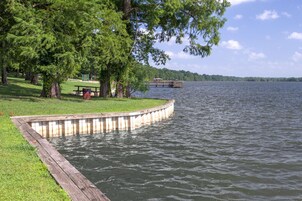 Un parque junto al lago con un muelle de madera, una mesa de picnic y bancos.