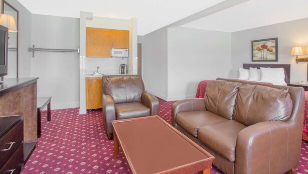 A compact hotel room with a kitchenette, a sofa, a coffee table, and a bed. - Days Inn by Wyndham Lake Village (Lake Village)