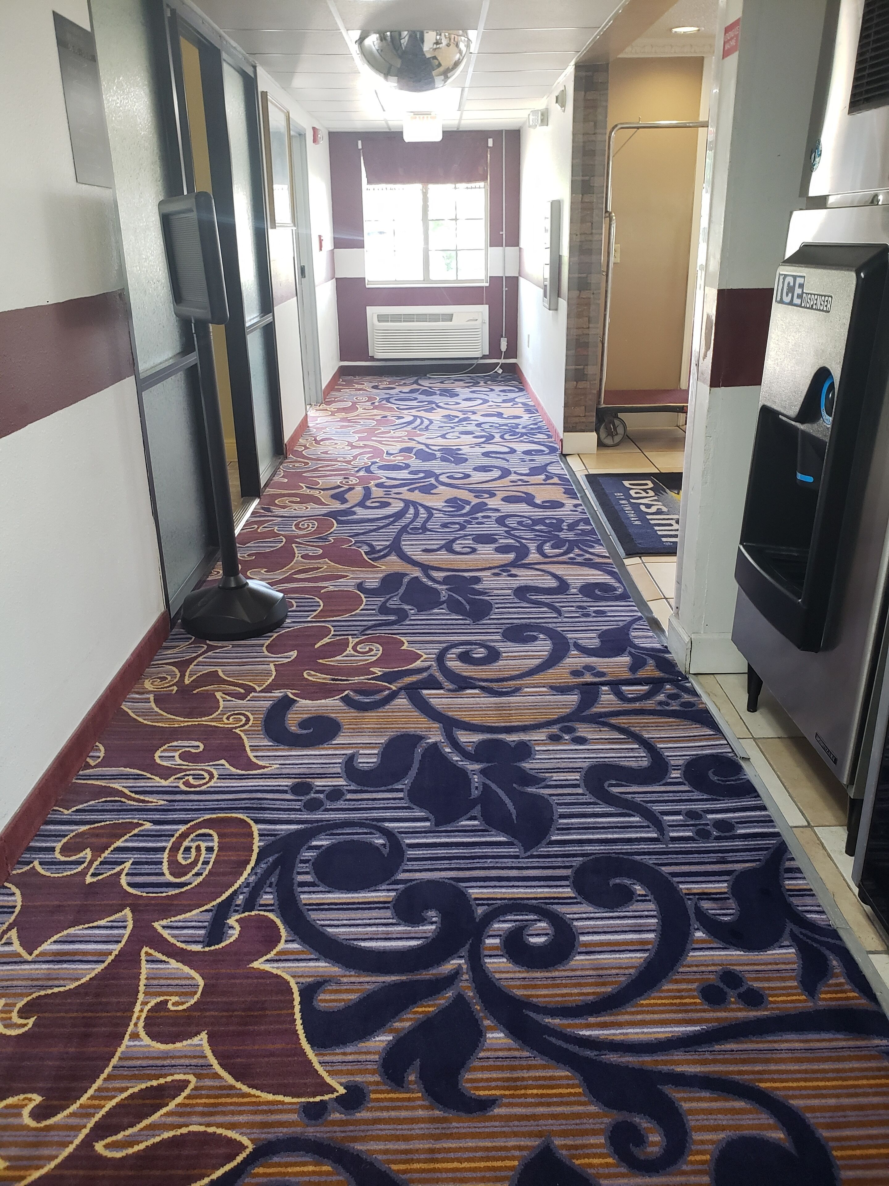 A hotel corridor with a patterned carpet, air conditioning units, and a water dispenser.