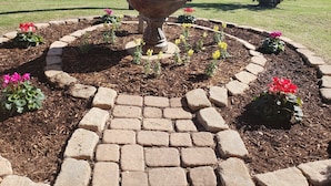 A garden with a central fountain, surrounded by a brick pathway and various plants. - Days Inn by Wyndham Lake Village (Lake Village)