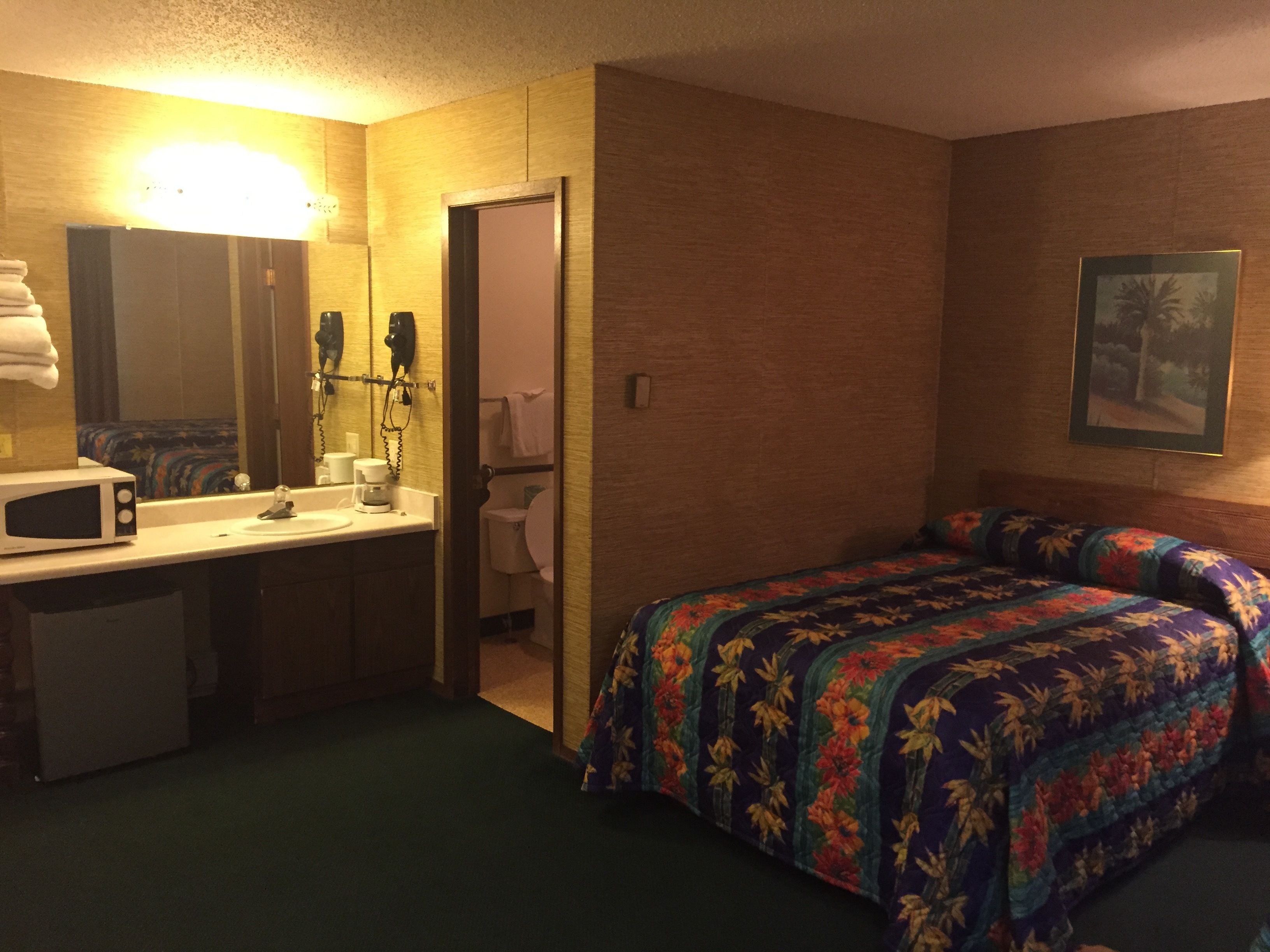 Habitación de hotel con cama, baño y kitchenette.